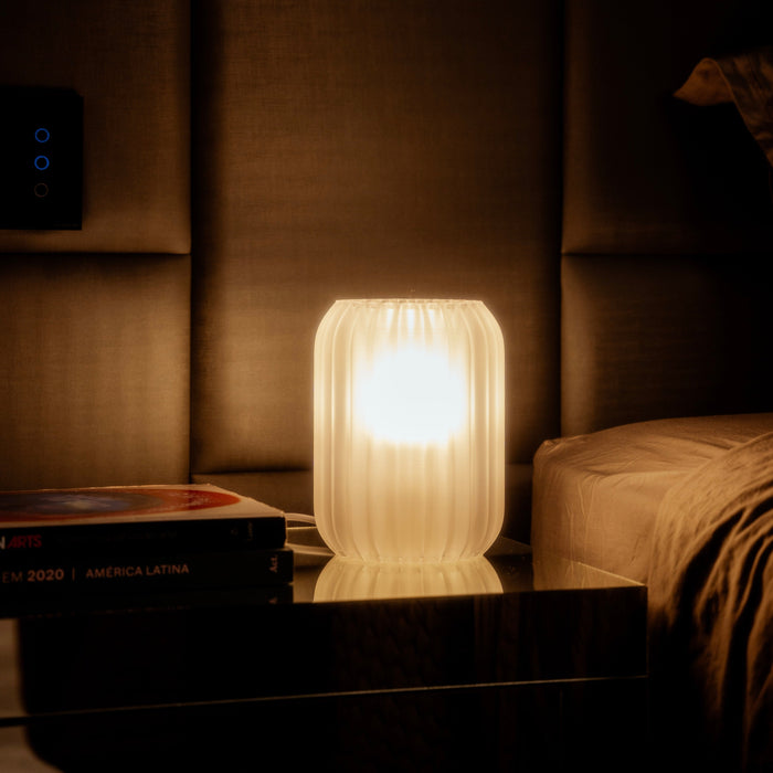 Luminária Aurora Translúcida acesa na cabeceira da cama