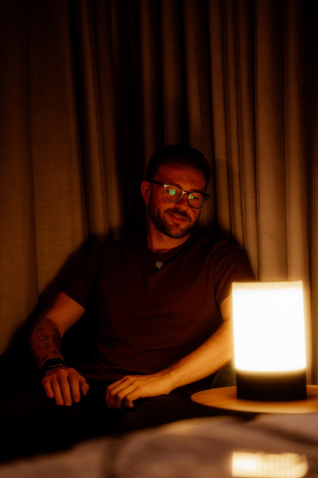 Matheus Ballesteros, fundador da Éttore, sentado à luz de uma luminária da marca
