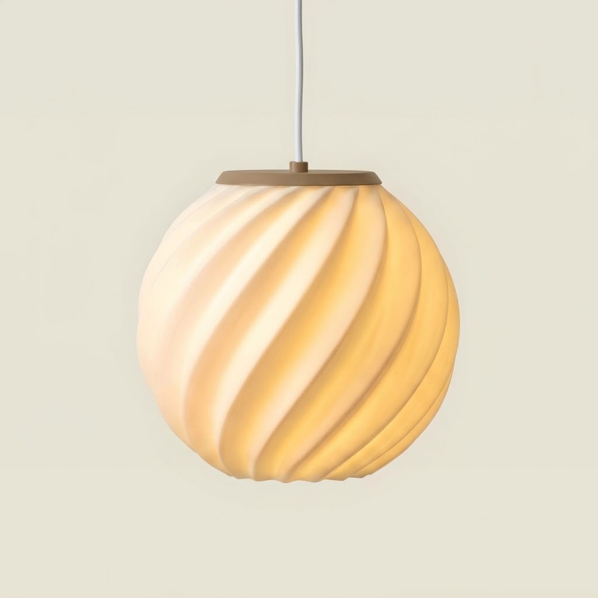 Pendente Maré com base bege da Éttore aceso, pendurado em estúdio de fundo creme