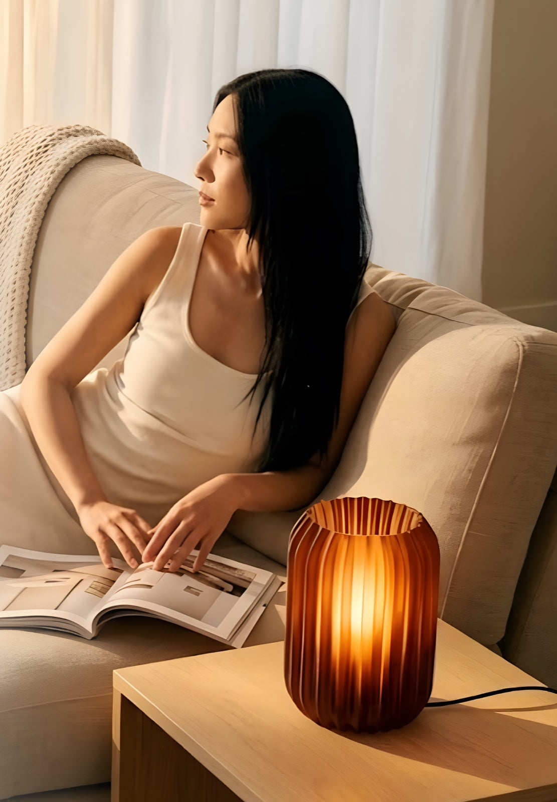 Mulher lendo no sofá ao lado de uma luminária acesa (foto conceito provisória, do bot)